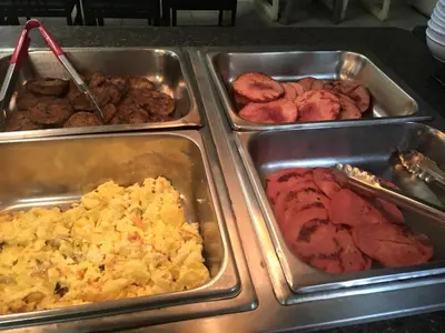 a buffet of different types of food in trays at PETRA Cabin Dorms Hostel in Wadi Musa