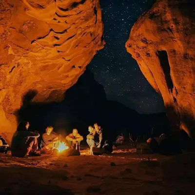 a group of people sitting around a fire at night at Wadi rum galaxy camp in Wadi Rum