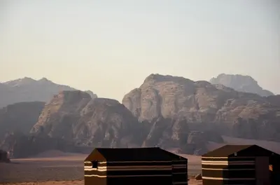 two huts in the desert with mountains in the background at Wadi rum galaxy camp in Wadi Rum