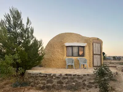 a small house with two chairs outside of it at Al-Nawatef ECO camp- Dana Nature Reserve in Dana