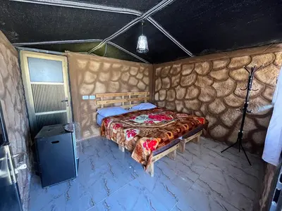 a bedroom with a bed and a stone wall at Al-Nawatef ECO camp- Dana Nature Reserve in Dana
