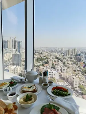 a table with plates of food on it with a view at Coral Tower Hotel by Hansa in Amman