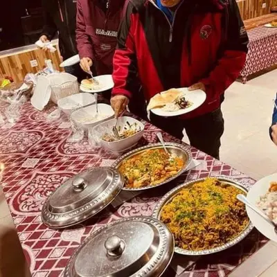 a group of people standing around a table with food at Wadi Rum Nova camp in Wadi Rum