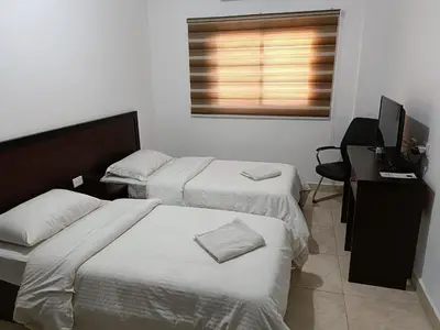 a bedroom with two beds and a desk with a computer at Happy Night Hostel in Wadi Musa