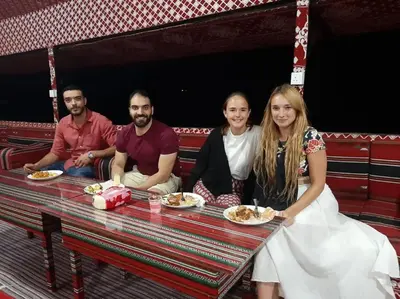 a group of people sitting at a table with food at WadiRum Mobile Camp in Wadi Rum