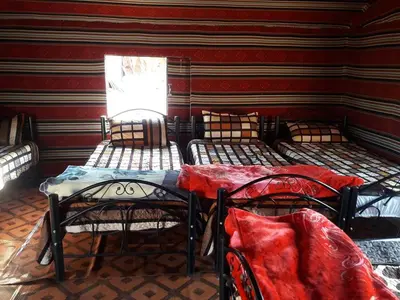 a room with three beds and a window at WadiRum Mobile Camp in Wadi Rum