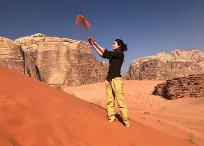 a woman standing in the desert flying a kite at WadiRum Mobile Camp in Wadi Rum