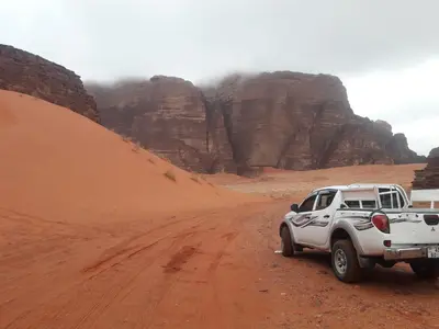 a white truck parked on a dirt road in the desert at WadiRum Mobile Camp in Wadi Rum