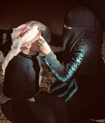 two men sitting on the ground with their heads together at Ammarin Bedouin Camp in Wadi Musa
