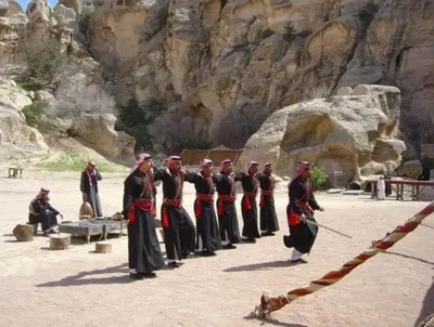 a group of men in traditional clothing standing in front of a mountain at Ammarin Bedouin Camp in Wadi Musa