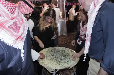 a group of people standing around a table with a pizza at Ammarin Bedouin Camp in Wadi Musa