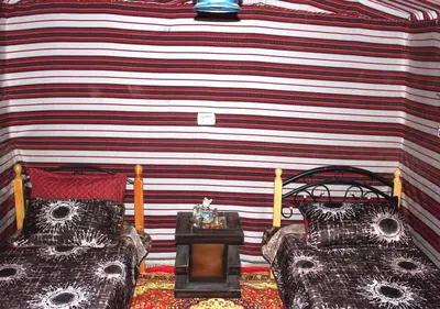 a room with two beds and a striped wall at Wadi Ghwere Camp مخيم وادي الغوير in Al Khuraybah