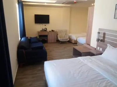 a hotel room with a bedroom with a bed and a chair at La Riva Hotel in Aqaba