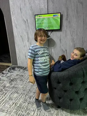 two young boys standing in a couch with a television at Bubble castle in Kerak