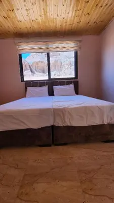 a bedroom with a large bed with two windows at Wadi Rum Quiet Sky in Wadi Rum
