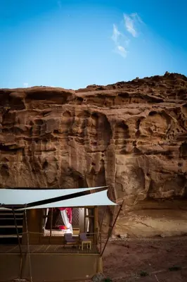 a building in front of a rock wall at Palmera Camp Wadi Rum in Wadi Rum