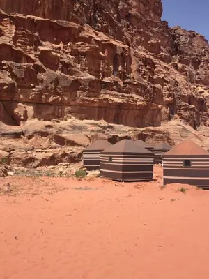 a group of buildings in the desert near a cliff at Wadi Rum in Wadi Rum