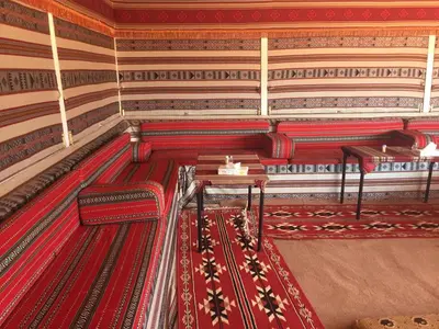 a room with a red carpet and two tables at Wadi Rum in Wadi Rum