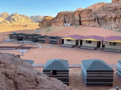 a group of buildings in the desert with mountains at Real Bedouin life &tour in Wadi Rum