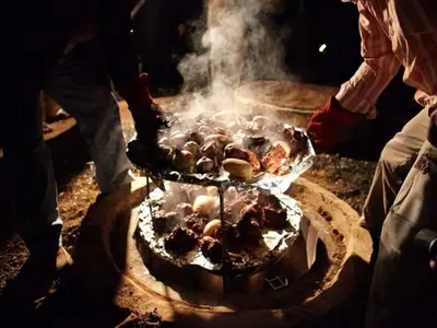 a person is cooking food on a grill at WADI RUM STAR WARS CAMP in Wadi Rum