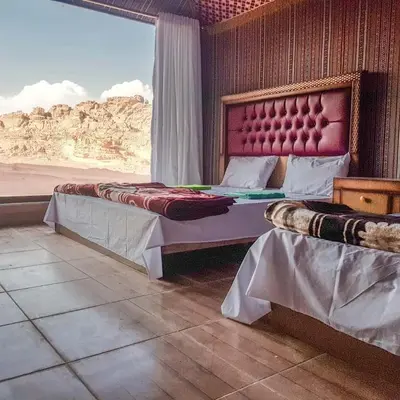 two beds in a room with a view of the desert at WADI RUM STAR WARS CAMP in Wadi Rum