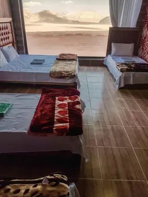 three beds in a room with a view of the desert at WADI RUM STAR WARS CAMP in Wadi Rum