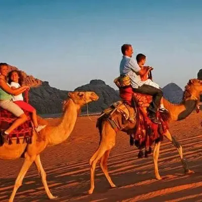 a group of people riding on the backs of camels in the desert at WADI RUM STAR WARS CAMP in Wadi Rum