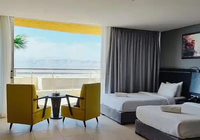a hotel room with two beds and a table and chairs at O Beach Hotel & Resort in Sowayma