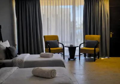 a hotel room with two beds and two chairs and a table at O Beach Hotel & Resort in Sowayma