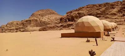 a group of domes in the desert with a mountain at Wadi Rum Maracanã camp in Wadi Rum