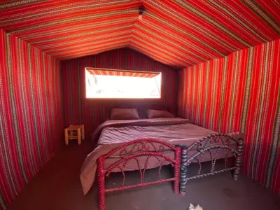 a small room with a bed in a red room at Wadirum momoo in Wadi Rum