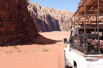 a truck driving through the desert with a canyon at Wadirum momoo in Wadi Rum