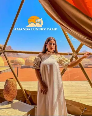 a woman in a white dress standing next to a table at Amanda Luxury Camp in Wadi Rum