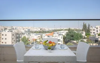 a table with a bowl of fruit on a balcony at Triple A Hotel Suites in Amman