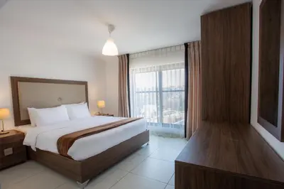 a bedroom with a bed and a large window at Triple A Hotel Suites in Amman