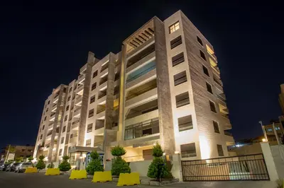 a large building at night with lights on at Triple A Hotel Suites in Amman