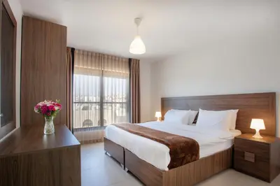 a bedroom with a large bed and a vase of flowers at Triple A Hotel Suites in Amman