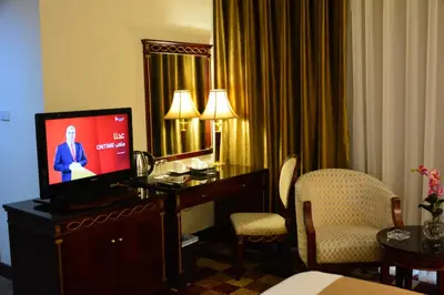 a hotel room with a television on a desk with chairs at Rakeen Hotel in Amman