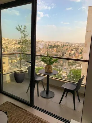 a balcony with a table and chairs and a large window at Nu Fifty Two in Amman