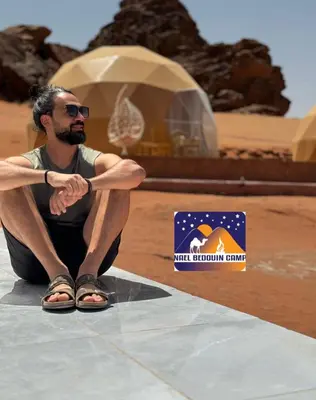a man sitting on a table in the desert at NAEL BEDOUIN lUXURY CAMP in Wadi Rum