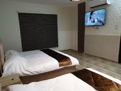 a bedroom with two beds and a flat screen tv at atoom studio in Jerash