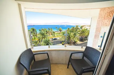 a balcony with two chairs and a view of the ocean at Joar Beach Hotel in Aqaba