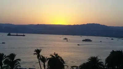 a sunset over a large body of water with boats at Joar Beach Hotel in Aqaba