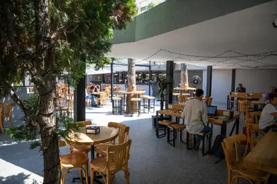 a man sitting at a restaurant with tables and chairs at Dali House in Amman