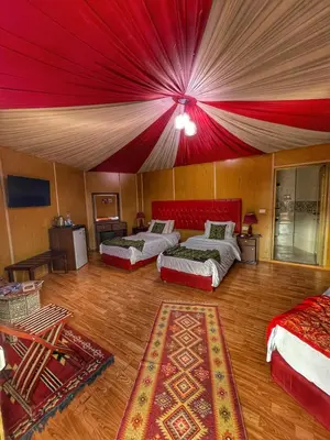 a room with two beds and a red ceiling at Rum Oasis Luxury Camp in Wadi Rum