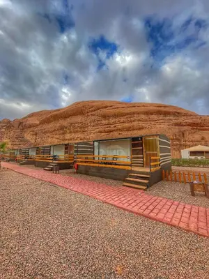 a building with benches in front of a mountain at Rum Oasis Luxury Camp in Wadi Rum