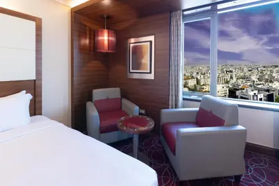 a hotel room with a bed and a chair and a window at Crowne Plaza Amman by IHG in Amman