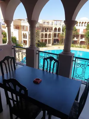 a table on a balcony with a view of a pool at Gorgeous Pool View Apartment - Tala Bay Resort, Aqaba in Aqaba