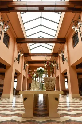 a lobby with a glass ceiling with flowers in vases at Kempinski Hotel Ishtar Dead Sea in Sowayma