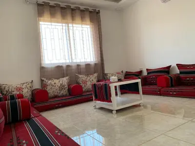 a living room with red couches and a table at Gedara Guesthouse: enjoy unforgettable scenes in Um Qeis